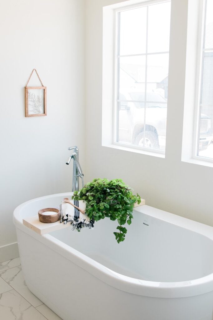 a beautiful white freestanding tub in a large bathroom with two windows 