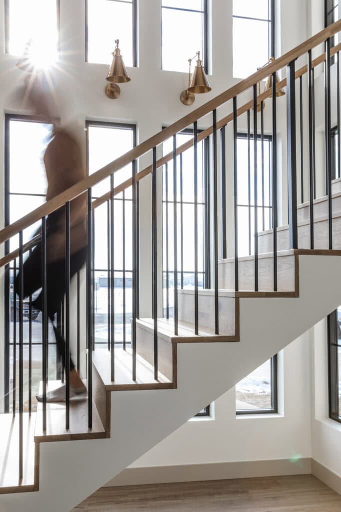 an example of a series of four sconces that march upward with the staircase at a custom home designed and built by Meg & Co in Twin Falls Idaho