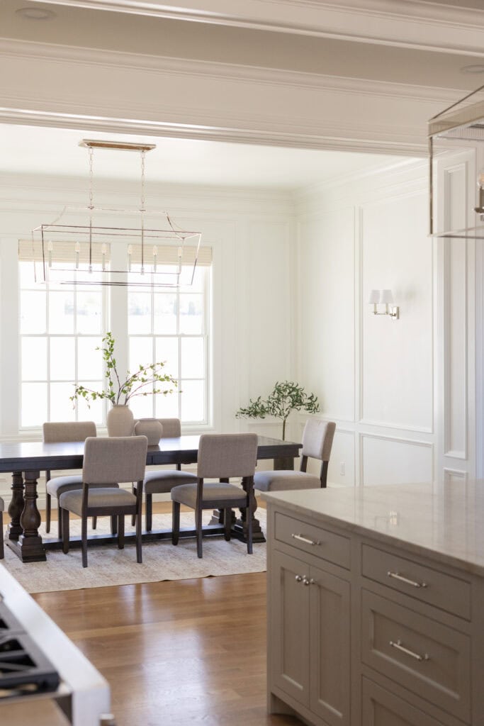 In order to create this beautiful dining room design our team at Meg & Co added Wainscoting Panels, sounded fun sconces and beautiful furniture