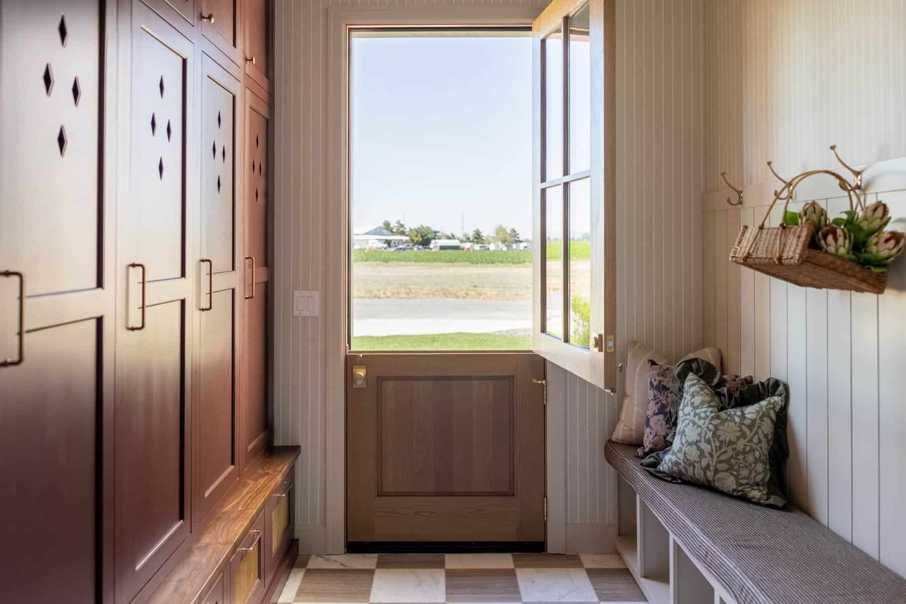 A mudroom with a unique door with separate openings for the top and bottom sections and a beautiful tile floor.