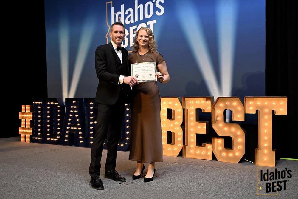 Two people hold an award certificate on stage at the 2026 Idaho’s Best Awards ceremony.