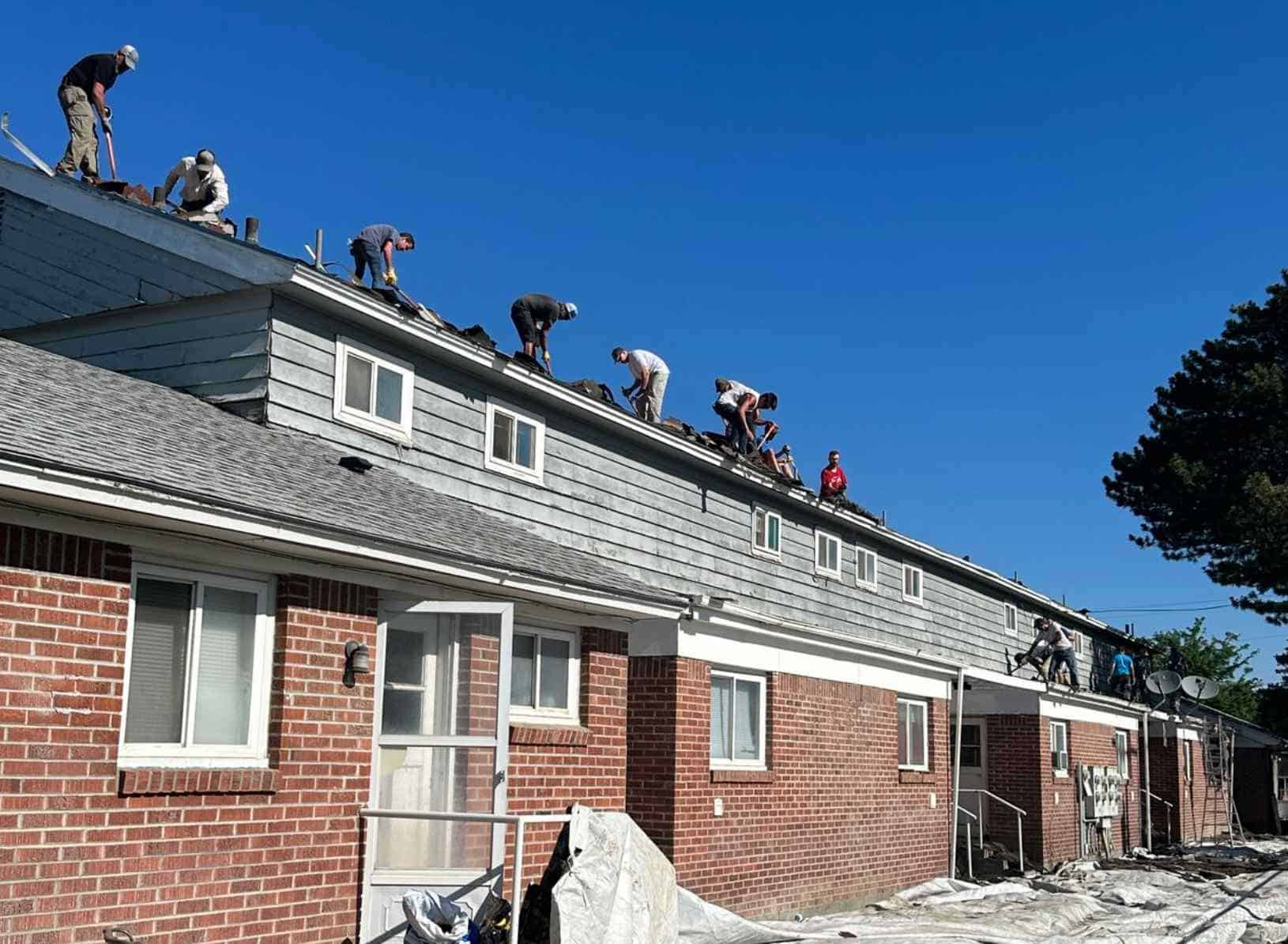 Construction crew works across the roof of the Valley House residential building during renovation.