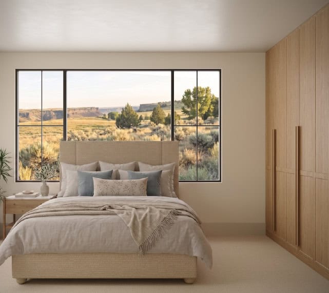 Bedroom - Custom Home Hailey Idaho Guest bedroom in The Merrick featuring custom wood wardrobes, a large picture window, neutral finishes, and views of the Idaho landscape.