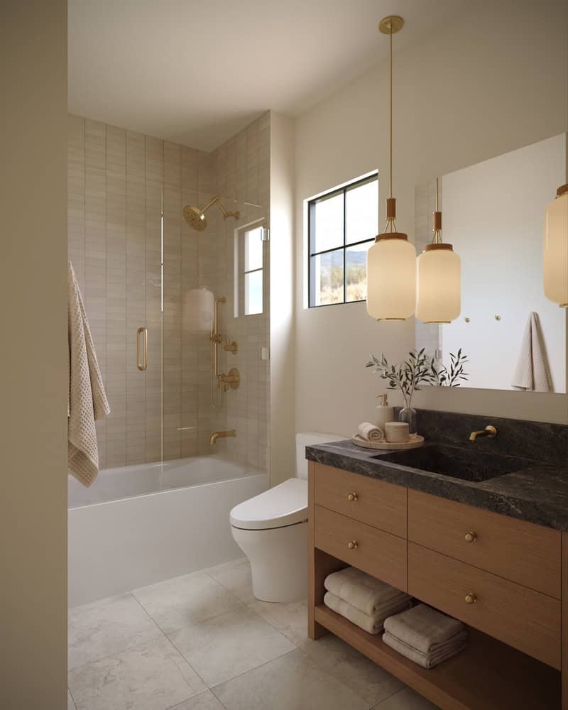 The Merrick Bathroom - Luxury Custom Home Hailey Idaho Bathroom in The Merrick featuring a warm wood vanity, dark stone countertop, natural tile, bathtub, and brass fixtures.