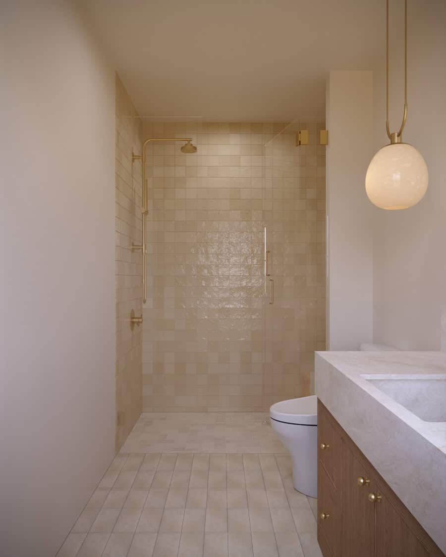 The Merrick Bathroom Three - Luxury Custom Home Hailey Idaho Guest bathroom in The Merrick featuring a wood vanity, light natural tile, walk-in shower, and warm brass fixtures.