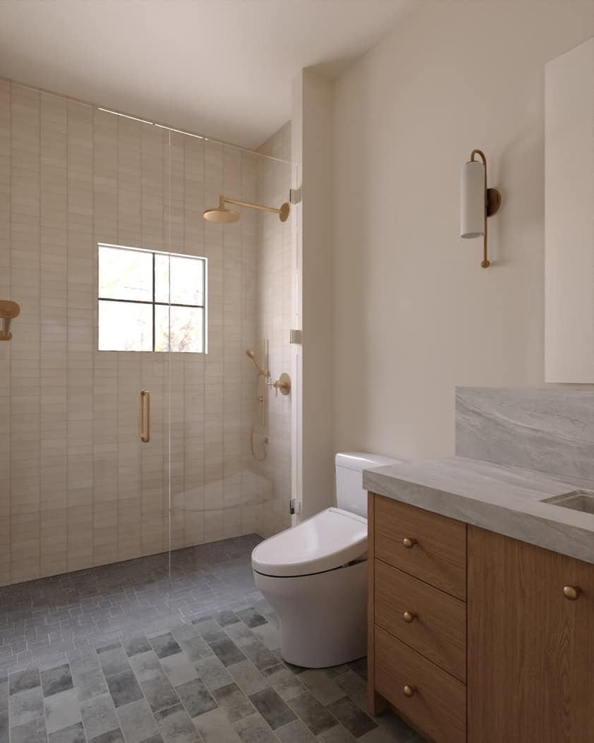 The Merrick Junior Suite Bathroom - Luxury Custom Home Hailey Idaho Junior suite bathroom in The Merrick featuring a wood vanity, natural tile, brass fixtures, and a walk-in shower.