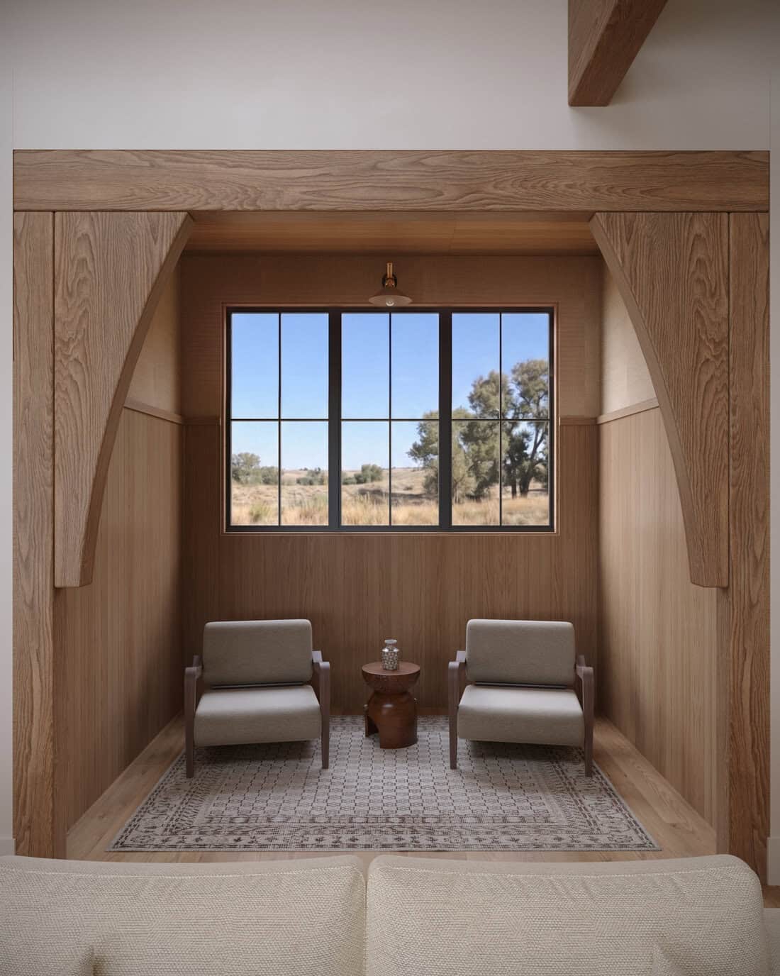 Intimate living room nook in The Merrick featuring warm wood paneling, built-in seating, and a large window overlooking the Idaho landscape.